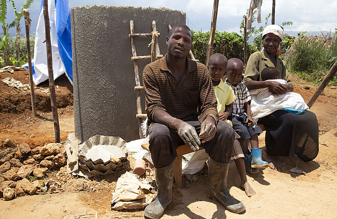 Eine Familie vor ihrem neu gebauten Wassertank. Bild: Anna Abel, TearFund Schweiz