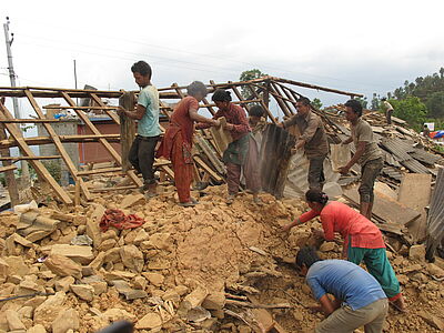 Nach dem schweren Erdbeben in Nepal räumen die Menschen die Trümmer eines zerstörten Hauses auf.