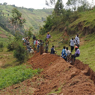 Dorfbewohner in Uganda graben einen Kanal, um ihre Felder vor Erosion und Überschwemmung zu schützen.