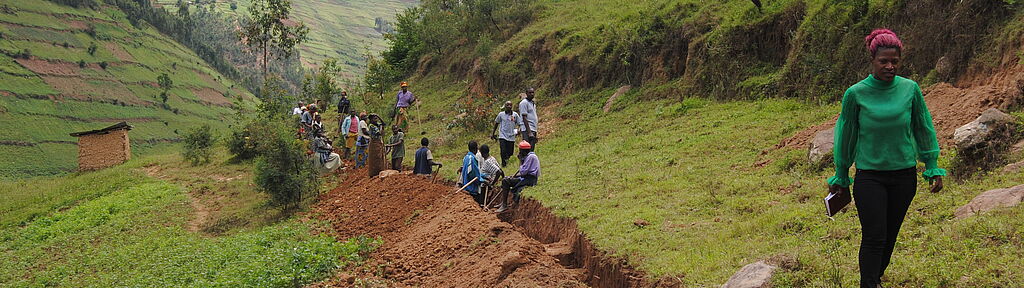 Dorfbewohner in Uganda graben einen Kanal, um ihre Felder vor Erosion und Überschwemmung zu schützen.