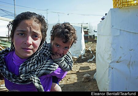 Ein irakisches Mädchen trägt seinen kleinen Bruder in einem der Flüchtlingscamps im Norden Iraks. Bild: Eleanor Bentall / TearFund UK