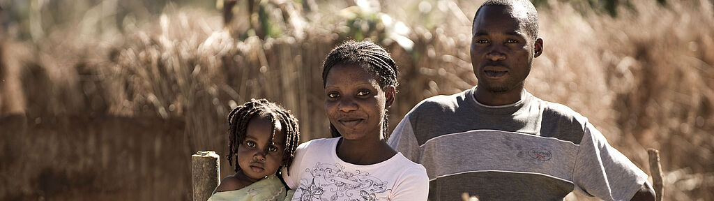 Eine junge afrikanische Familie lächelt in die Kamera.