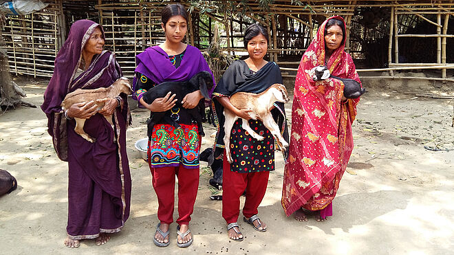 Vier farbig gekleidete Frauen halten je eine Ziege auf den Armen. Bild: Thomas Stahl