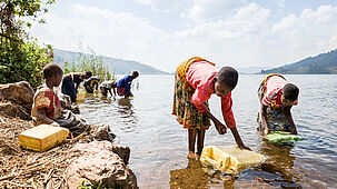 Zwei Mädchen shöpfen Wasser aus einem See.