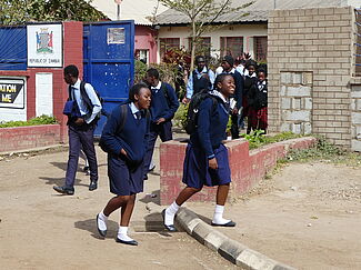 Schüler aus Sambia gehen nach Schulschluss lachend und schwatzend nach Hause