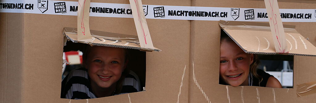 Zwei Kinder in einer selbstgebauten "Kartonhütte"