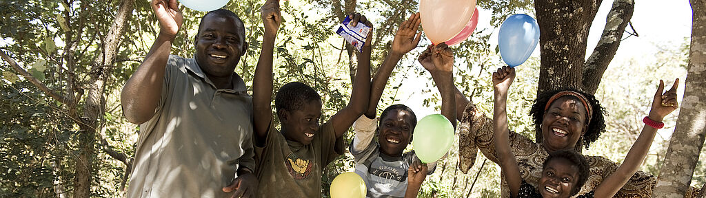 Afrikanische Familie hält lachend Ballone in die Luft