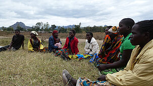 Eine Gruppe Malawischer Frauen und Männer sitzen zusammen in einem Kreis.