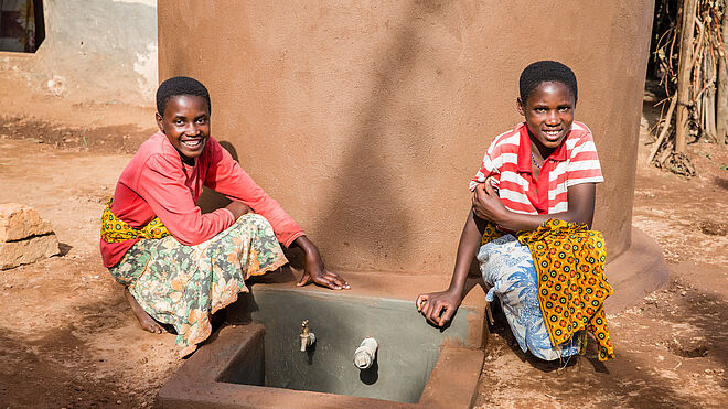 Zwei Mädchen neben dem Wassertank. Bild: Marcus Perkins, TearFund Schweiz